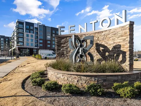 A new apartment building and the stone Fenton sign in Cary, NC under a blue sky