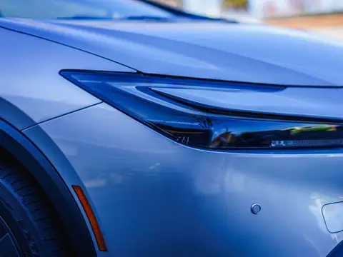 The blue front corner of a modern car with its headlamp and the round sensors in the bumper