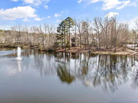 A lake with a fountain and bare trees reflected in the water in Knightdale, NC